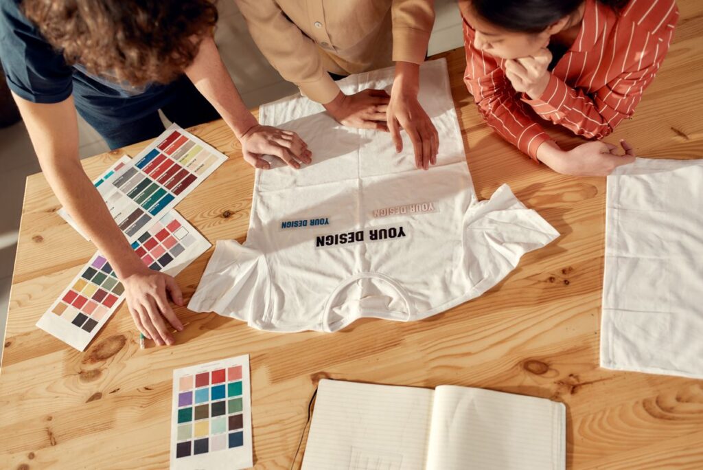 Team prüft Farbkarten und T-Shirt Entwurf am Tisch beim Firmenkleidung bedrucken mit individuellen Designs
