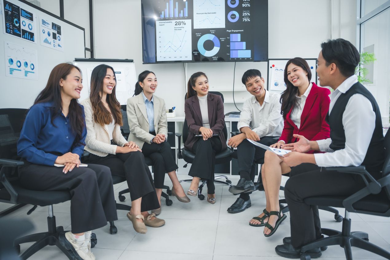 KI Entwicklung und Innovationskultur im Unternehmen, Teammeeting mit Datenvisualisierung auf Screens im Hintergrund