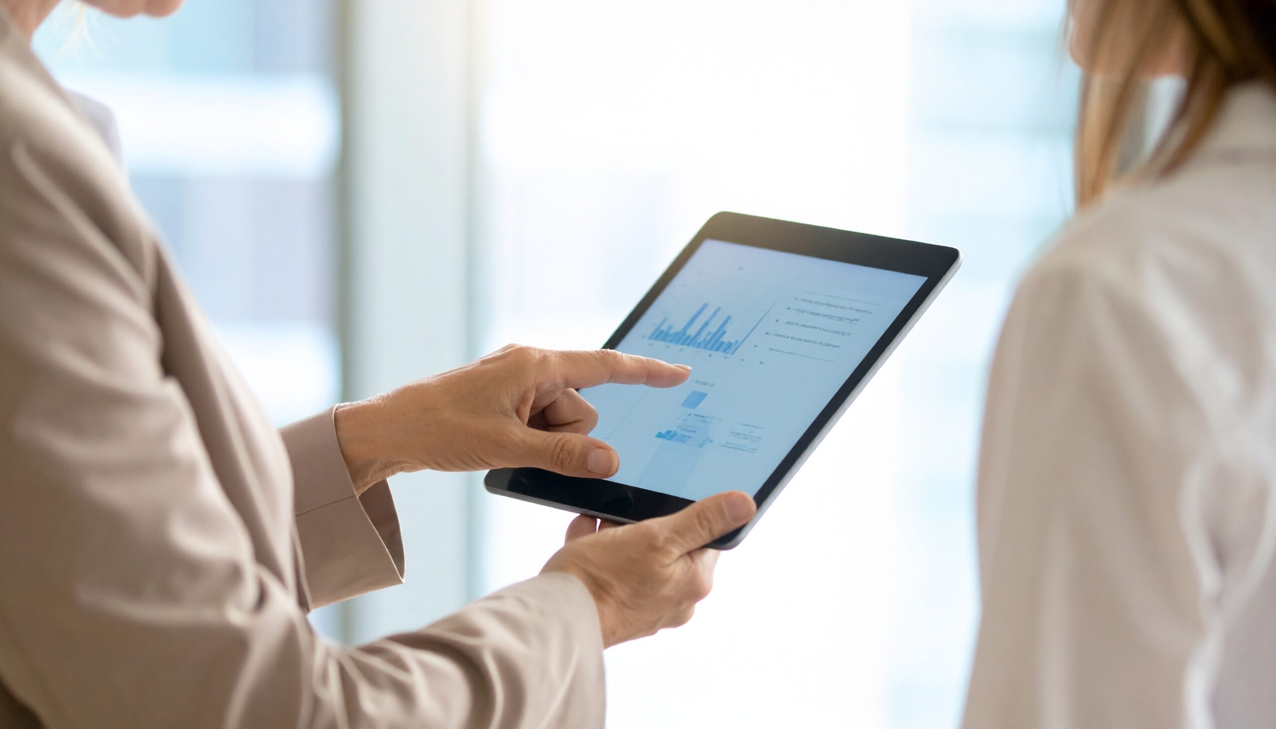 KI Entwicklung sichtbar in Datenanalyse auf Tablet, zwei Personen im Gespraech ueber digitale Businessprozesse