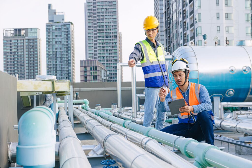 Zisterne auf Gewerbedach mit moderner Rohrtechnik – zwei Techniker prüfen Regenwassersystem zur nachhaltigen Nutzung im Unternehmen