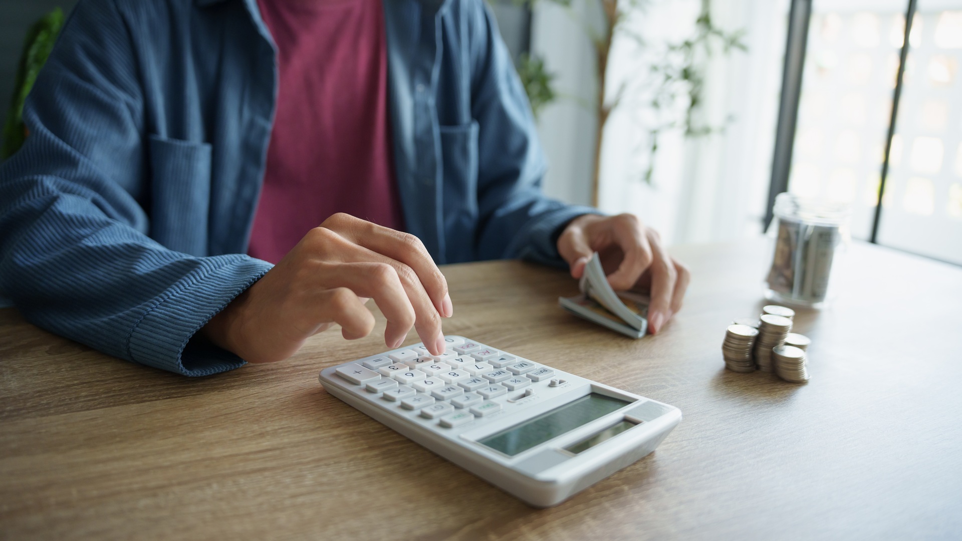 Person zählt Geld mit Rechner | Gehaltsabrechnung online